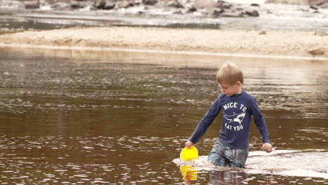 Niño-Recogiendo-Agua-En-Un-Balde-De-Un-Lago,-Cámara-Lenta