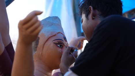 artisan meticulously paints a durga puja idol