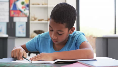 En-La-Escuela,-Un-Joven-Estudiante-Afroamericano-Se-Centra-En-Su-Cuaderno-En-El-Aula.