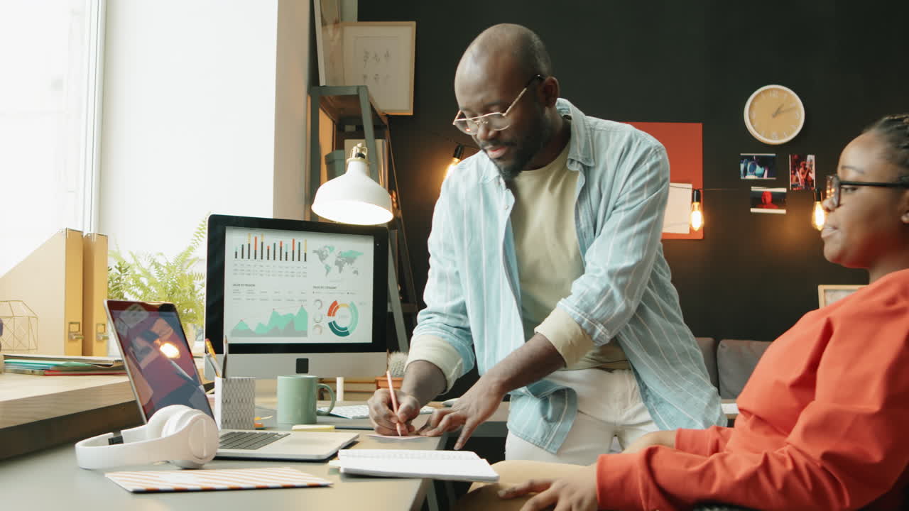 Black Woman in Wheelchair Working with Colleague in Home Office