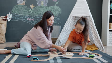 mother and daughter playing with wooden trains