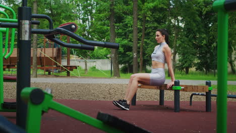 A-female-athlete-performs-reverse-exercises-on-a-bench-in-a-Park-in-slow-motion.-Beautiful-woman-playing-sports-in-the-Park