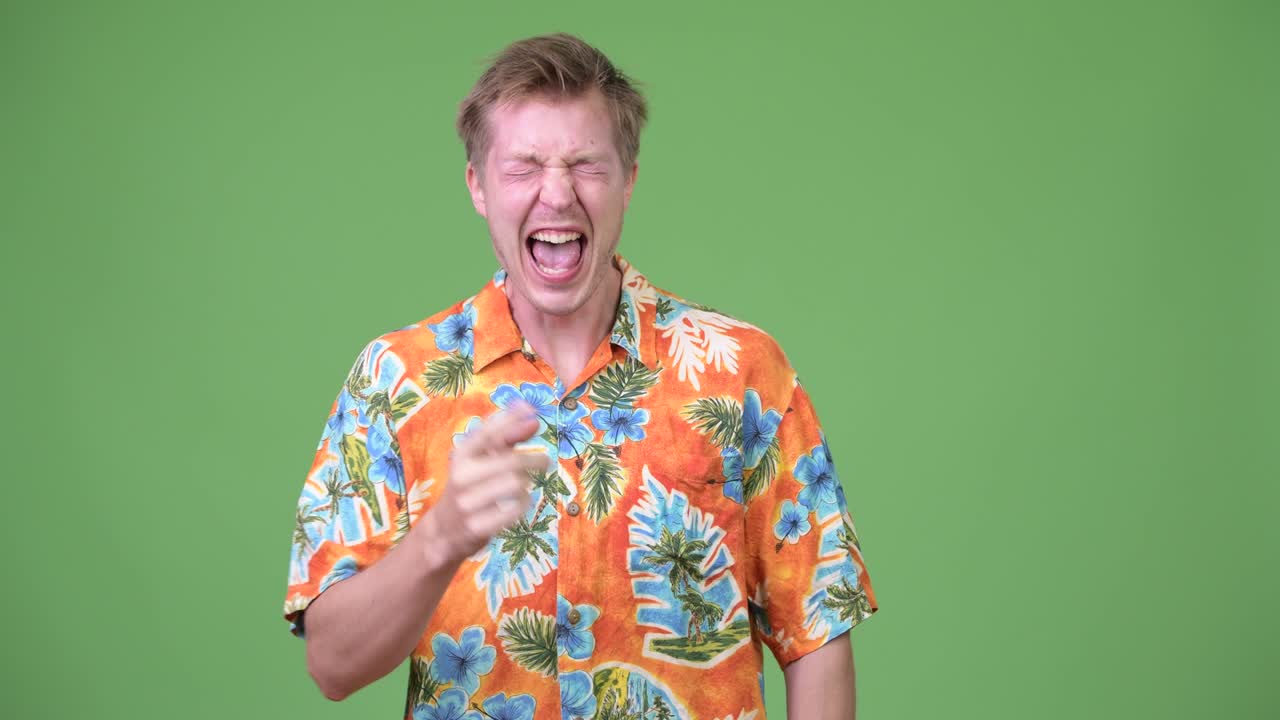 Young handsome tourist man laughing