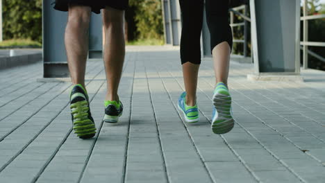 Camera-Focuses-The-Feet-Of-Young-Jogger-Couple-Running-In-The-Stadium-In-Summer