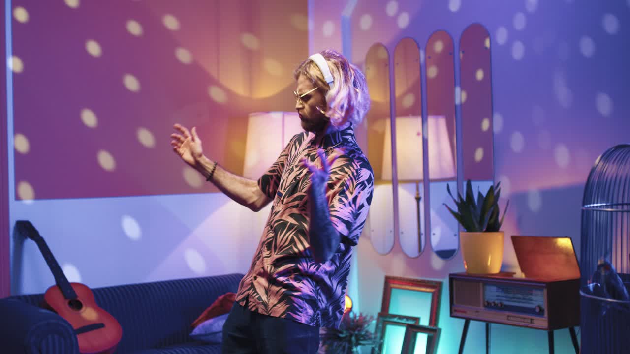 집에 있는 복고풍 파티에서 헤드폰을 끼고 선글라스를 끼고 정력적으로 춤을 추는 젊은 세련된 백인 남자