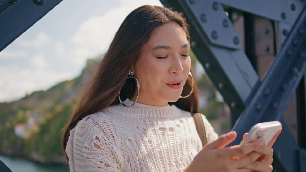 Laughing model reading sms on bridge closeup. Funny girl typing mobile phone
