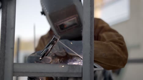 welder uses arc welder to tack together sections of angle iron- slow mo dolly back