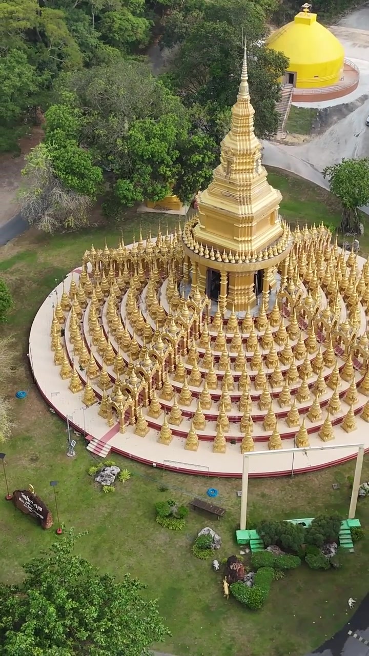 Orbita aerea verticale attorno al tempio della pagoda dorata di Wat Pa Sawang Bun, circondato dalla lussureggiante campagna tropicale di Saraburi in Thailandia