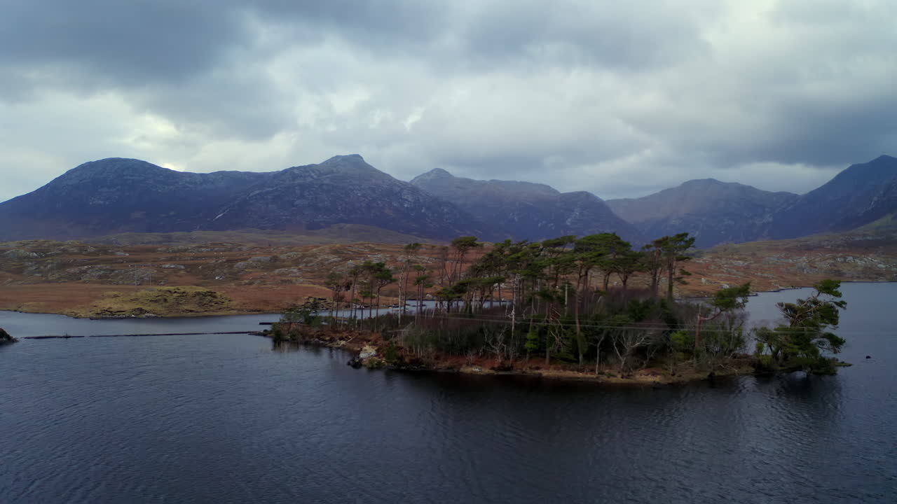 Dynamic aerial shot unveiling Connemara’s twilight landscape, with trees on a foreground island, Galway