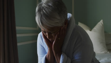 depressed senior mixed race woman at home with head in hands