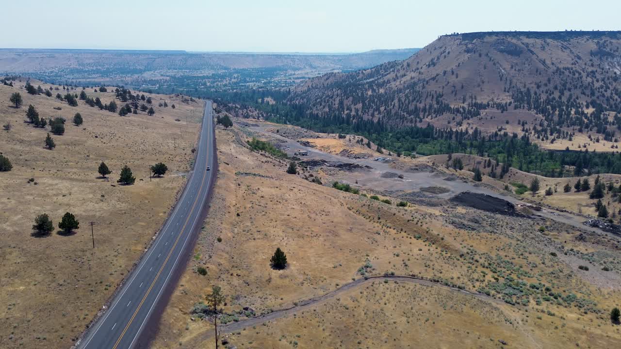 Drone aerial landscape of road highway freeway with rolling hills mountains cliffs desert countryside Warm Springs Indian Reservation Oregon USA America nature outdoors travel