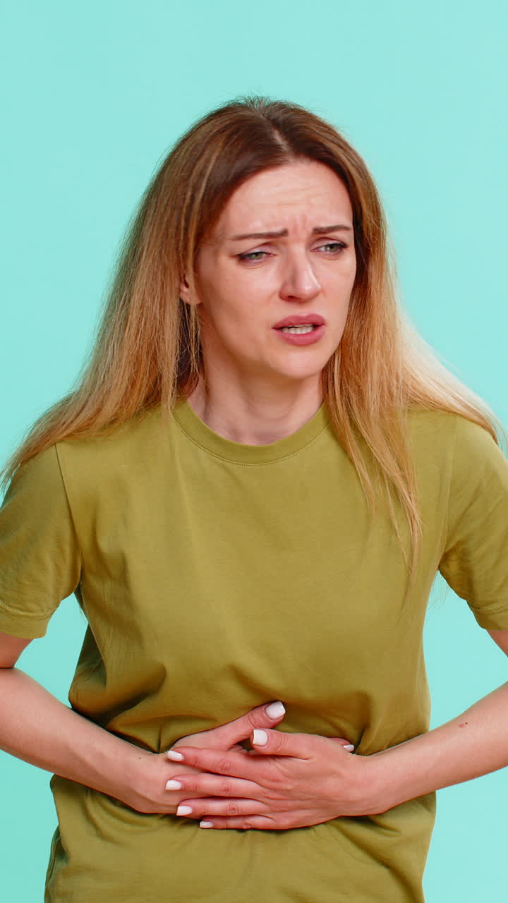 Donna che tocca la pancia con espressione sofferente a causa di crampi mestruali o intossicazione alimentare
