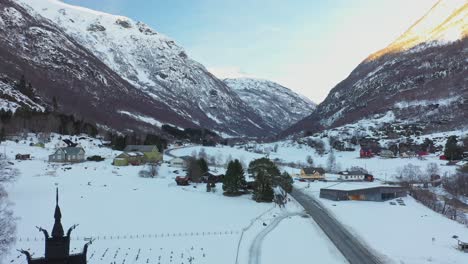 valle de borgund cerca de laerdal noruega - antena en movimiento hacia arriba cerca de stave churc que revela una vista panorámica durante la puesta de sol de invierno
