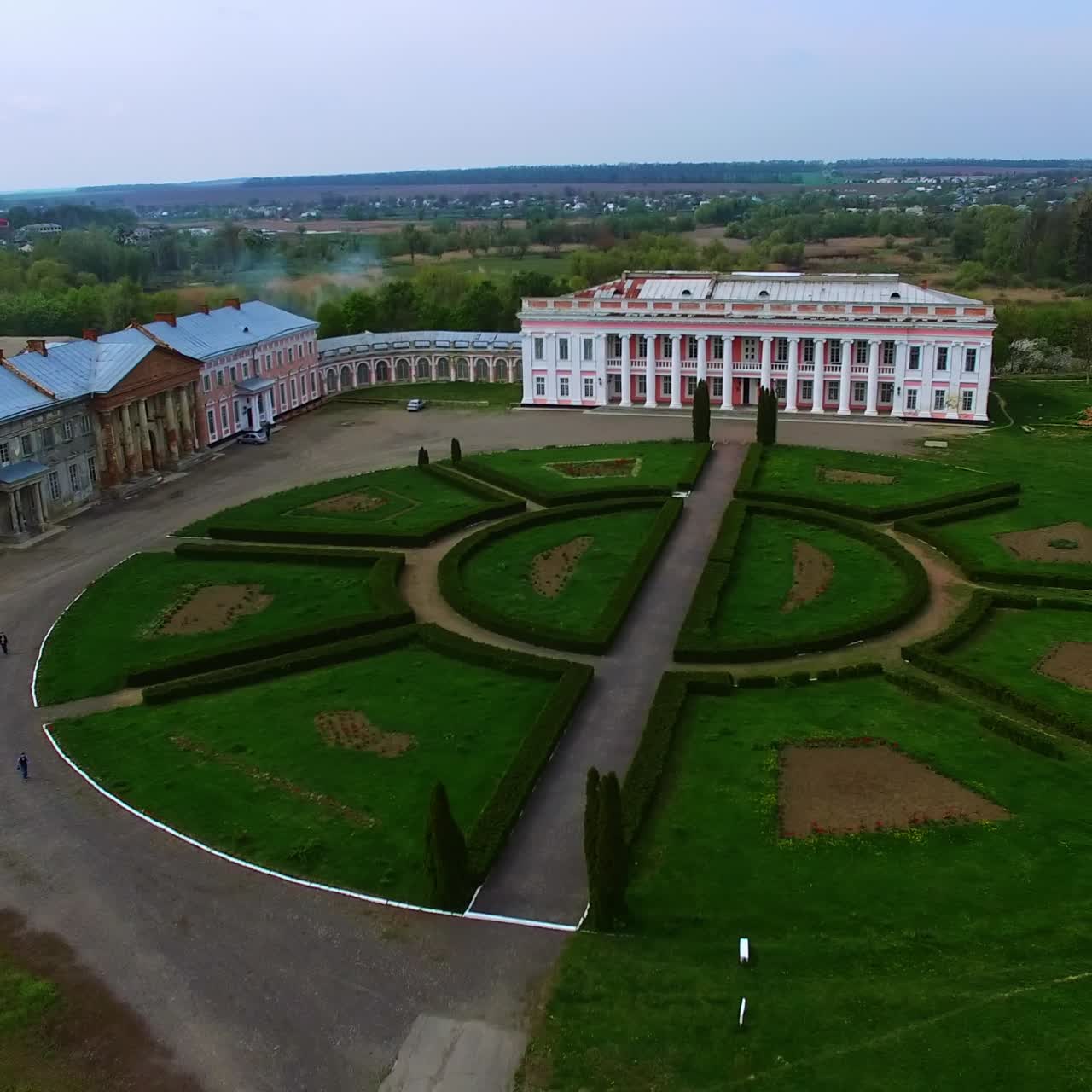 Magnificent old-fashioned palace with white columns. Drone distancing from a building over the well-kept territory