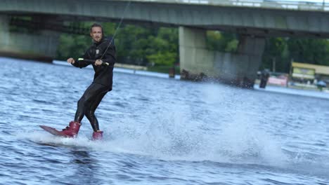 energy sportsman in black swimsuit wakeboarding. wakeboarder surfing across lake