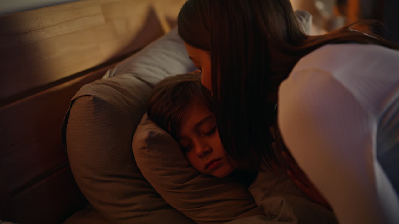 Little boy going bed closing eyes lying home bedding closeup. Mother son bedtime