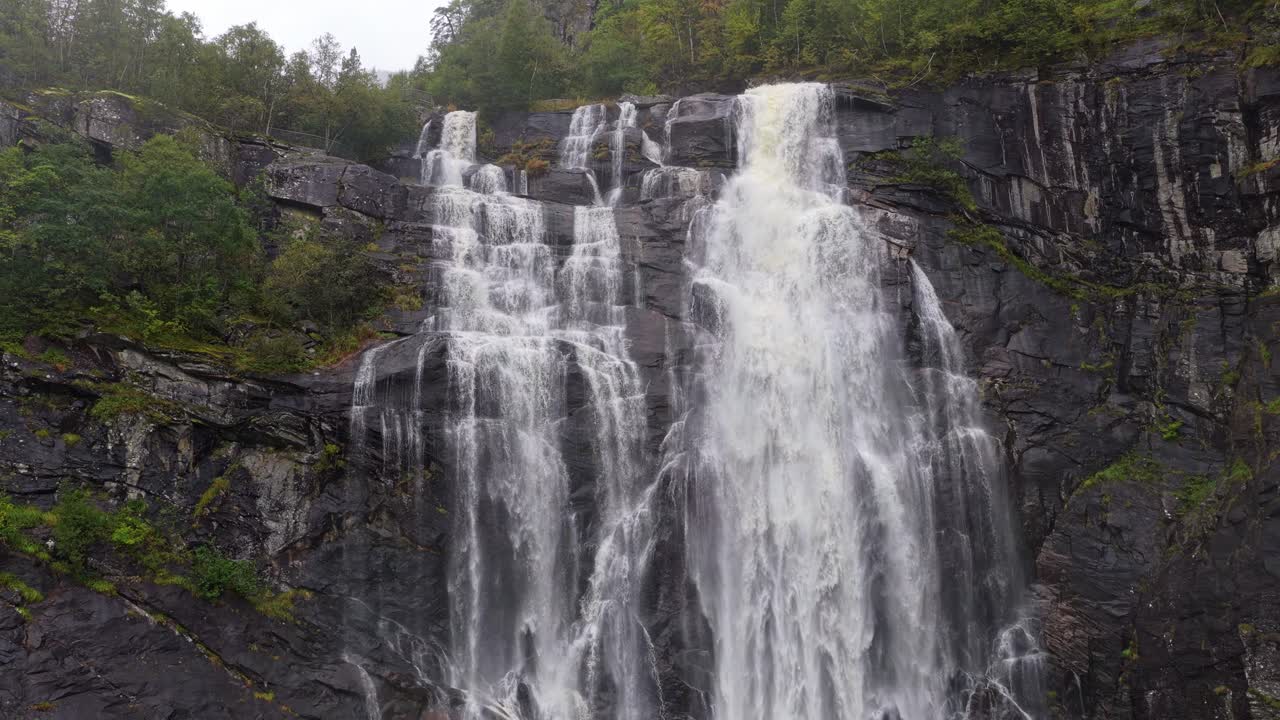 Aerial view of Skjervefossen falls and man framed by misty Norway cliffs