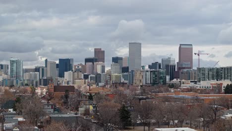 Aerial-telephoto-pan-over-Denver-suburb-with-city-skyscrapers-in-distance-on-overcast-day