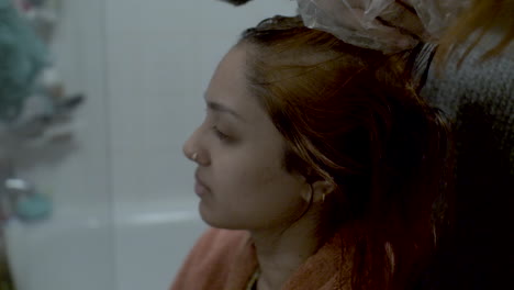 side angle shot of a mother helping her daughter dye her hair