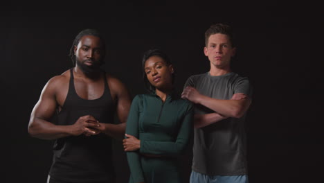 studio portrait of serious and determined male and female athletes in fitness clothing training shot against black background 3