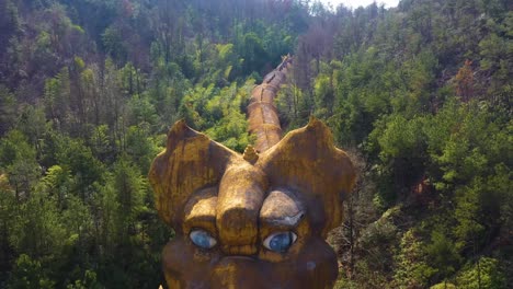 aerial view of the abandoned dragon park in jiuhua mountain, anhui province, china. the image features a massive, decaying dragon sculpture lying among the trees.