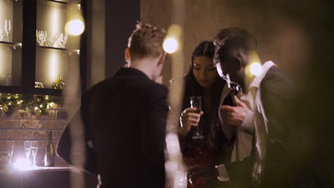 group friends wearing stylish clothes while talking and holding champagne glasses at new year's party 2