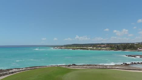 coastal establishing aerial of bright green fairways and palm trees lining the oceanfront of tropical resort