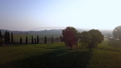 Farm-fields-with-water-hole-in-Tuscany-Italy-on-a-morning-with-heavy-fog,-Aerial-pan-left-shot