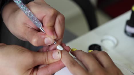 esteticista anónima aplicando laca en las uñas de las clientes femeninas