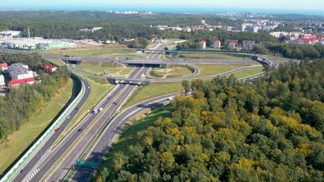 aerial shot of a sprawling highway interchange surrounded by lush greenery and urban structures