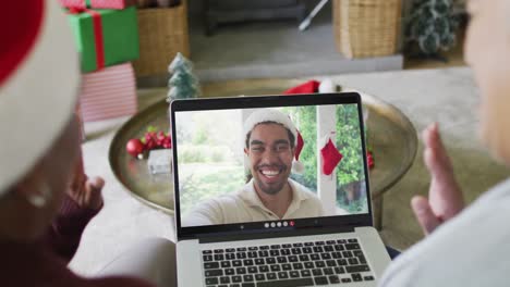 Senior-diverse-female-friends-using-laptop-for-christmas-video-call-with-smiling-friend-on-screen