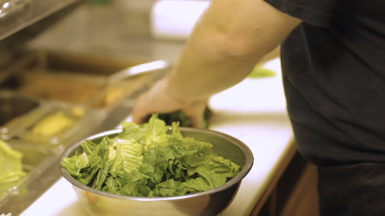 chef cortando lechuga en la cocina de un restaurante