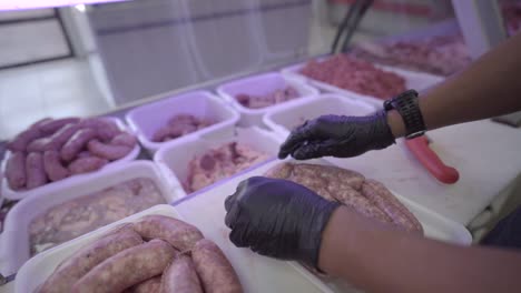 man prepares sausages to sell in a market butcher shop