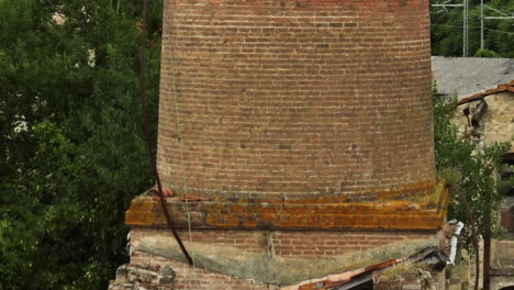 Old-abandoned-ceramic-factory-with-weathered-brick-structures-in-Italy,-surrounded-by-greenery