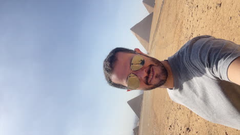 Tourist-man-makes-victory-sign-with-the-pyramids-of-Giza-in-the-background,-Egypt