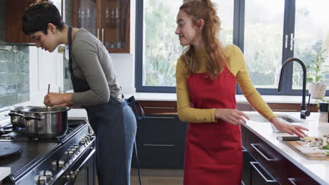 Feliz-Pareja-De-Lesbianas-Caucásicas-Preparando-Comida-Y-Abrazándose-En-La-Soleada-Cocina