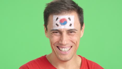 man with a south korean flag painted on the face smiling