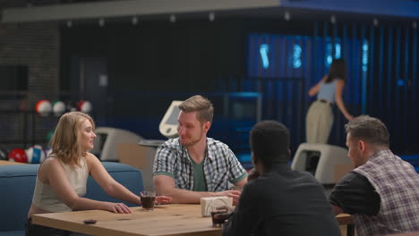 a caucasian brunette woman knocks out a strike in a bowling alley and runs up to her friends to rejoice together and give five together with friends to celebrate the victory