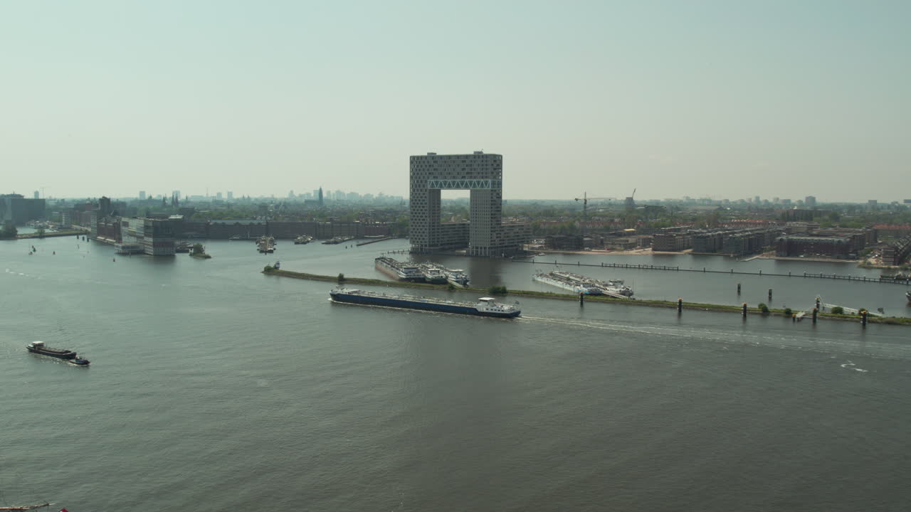 Lægtepram sejler på IJ-floden forbi Hotel Pontsteiger i Amsterdam, Holland