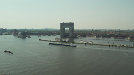 Barge-Cruising-In-The-IJ-River-Passing-By-Hotel-Pontsteiger-In-Amsterdam,-Netherlands