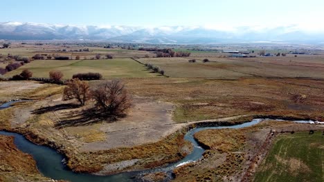 aerial drone footage of farmland with a creek in western utah