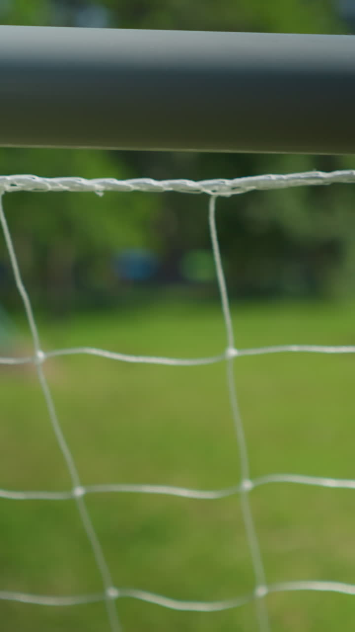 Close-up of a soccer goal net with a blurred view of a young boy walking away in the background