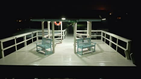 Reversing-drone-shot-of-a-gazebo-on-the-end-of-a-private-dock-on-a-Florida-lake,-with-security-camera-signs-and-flotation-device