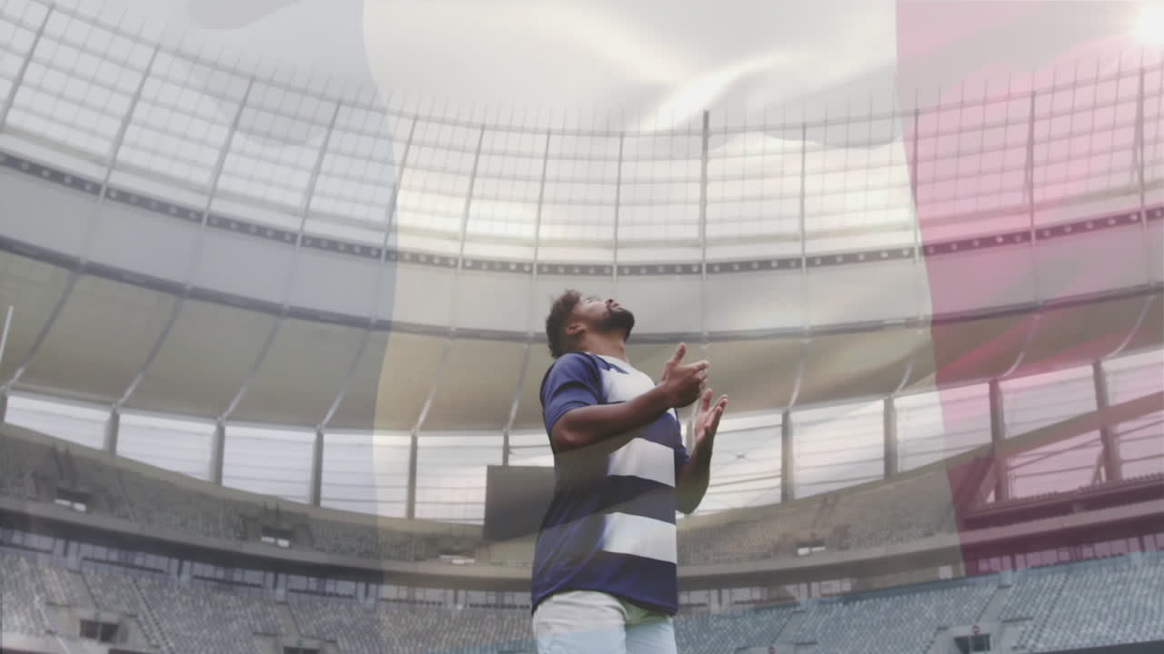 Catching rugby ball, player in striped jersey in large stadium during animation