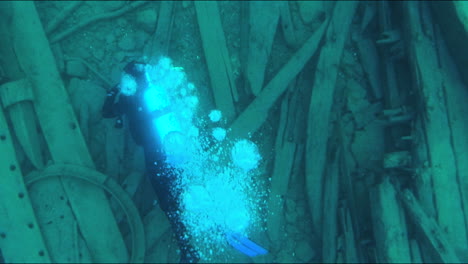 bubbles float up as a diver explores an underwater shipwreck