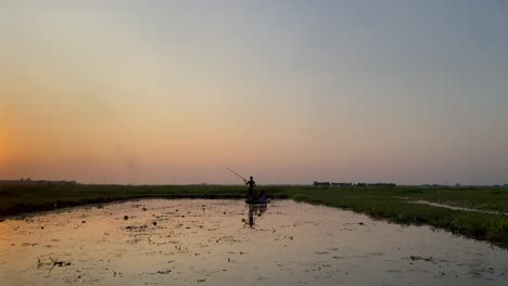 Beautiful-scene-of-a-village-sunset-where-a-man-is-rowing-boat-with-passengers-in-a-rural-village-lake-covered-with-planktons