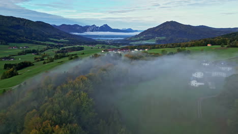 scenic views with layer of fog over the landscape with mountainous background in a green lush environment background, aerial panning shot