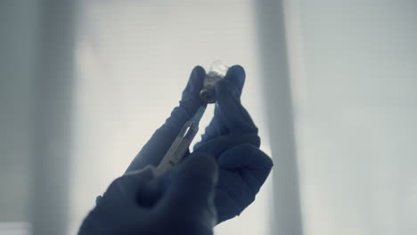 las manos del médico llenando la jeringa con medicamento antiviral sosteniendo el vial de cerca.
