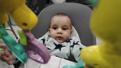 a charming scene of a 4-month-old engages joyfully in a baby bouncer, playing with delightful sensory toys