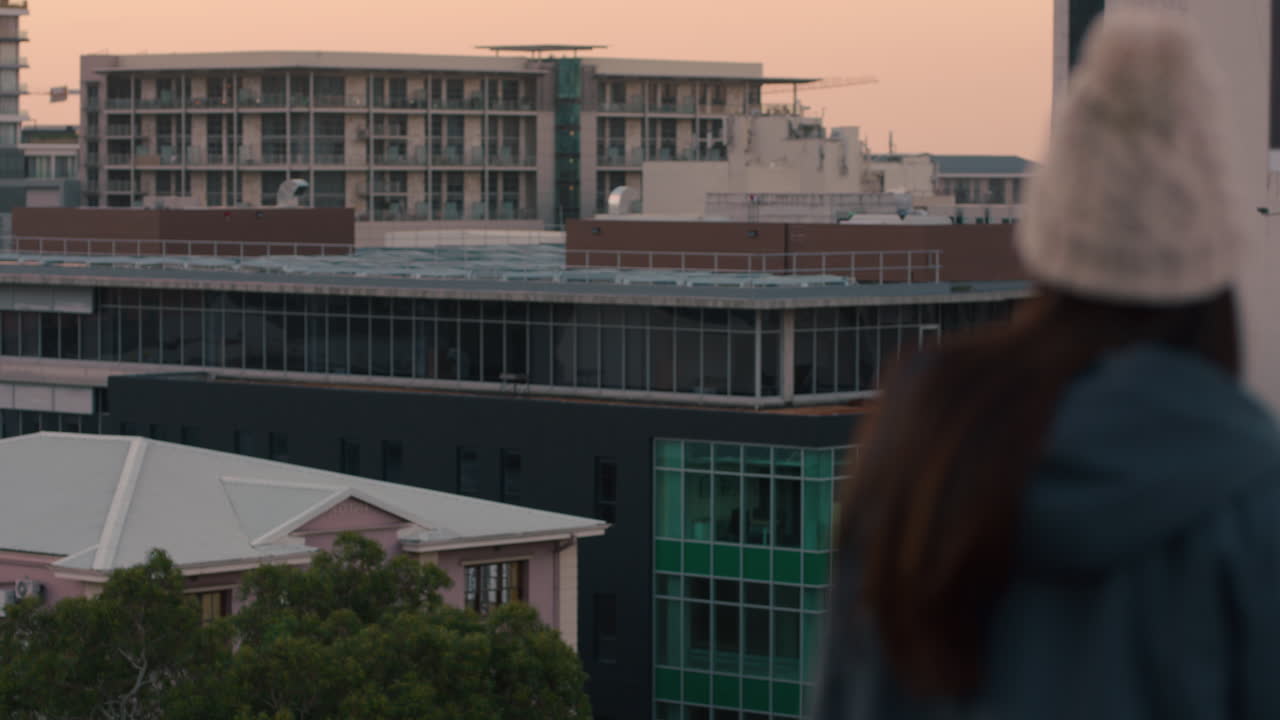 bella giovane donna caucasica che ride sul tetto al tramonto godendo di uno stile di vita di successo donna felice che guarda la vista dello skyline della città